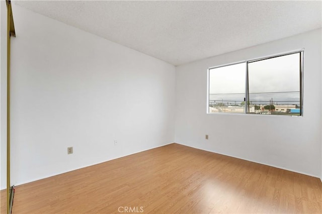 empty room with a textured ceiling and wood finished floors