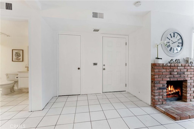 entrance foyer with light tile patterned floors, visible vents, and a fireplace