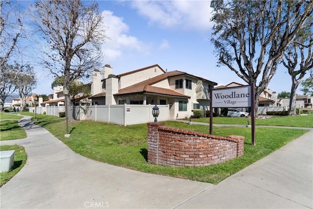 exterior space featuring a front yard, stucco siding, fence, and a chimney