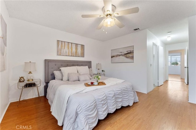 bedroom with visible vents, light wood-style floors, a ceiling fan, and a textured ceiling