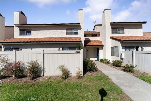 view of front facade featuring fence, a chimney, and stucco siding