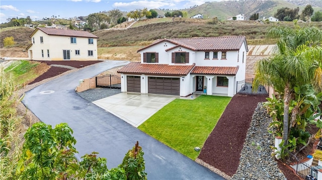 mediterranean / spanish house with stucco siding, a gate, fence, concrete driveway, and a tiled roof