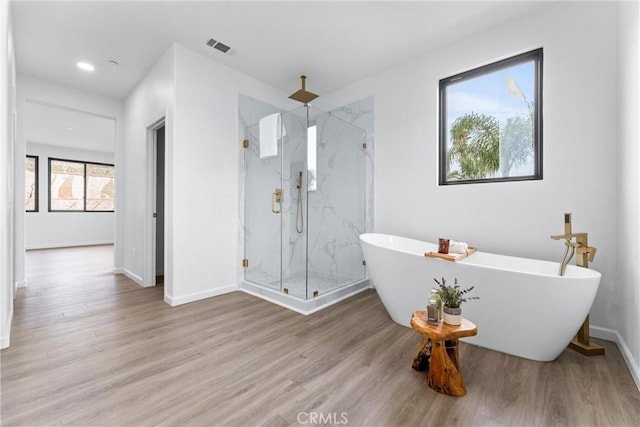 full bath with a marble finish shower, baseboards, a soaking tub, and wood finished floors