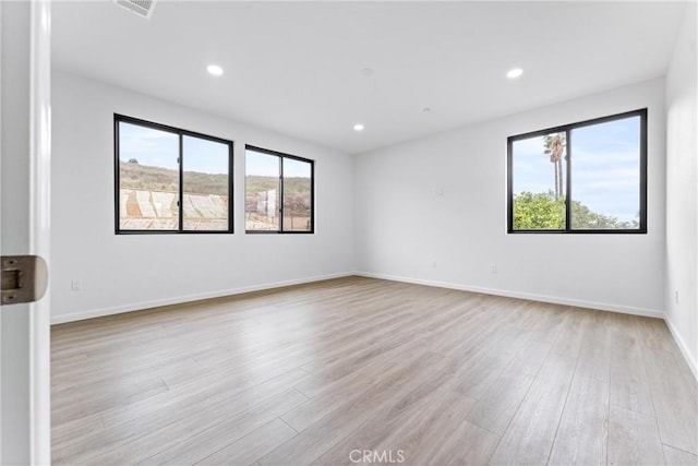 empty room featuring visible vents, recessed lighting, baseboards, and light wood-style floors