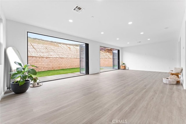 unfurnished living room with recessed lighting, visible vents, and wood finished floors