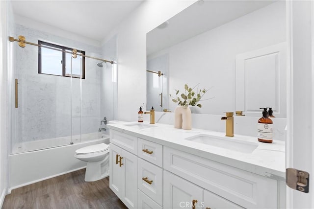 full bathroom with double vanity, enclosed tub / shower combo, toilet, and a sink