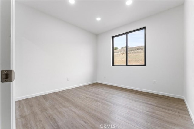 spare room with recessed lighting, baseboards, and wood finished floors