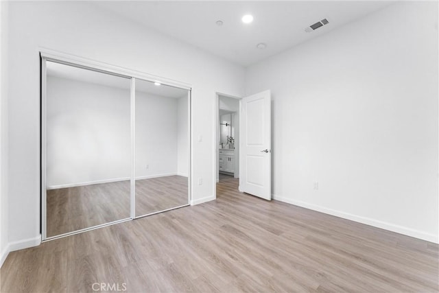 unfurnished bedroom with visible vents, baseboards, recessed lighting, wood finished floors, and a closet