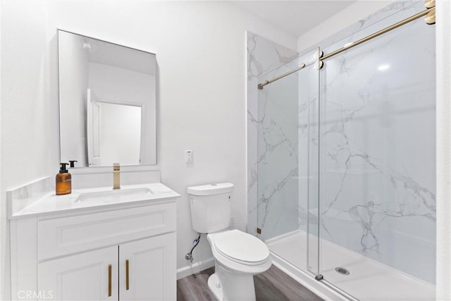 bathroom with toilet, wood finished floors, a marble finish shower, baseboards, and vanity