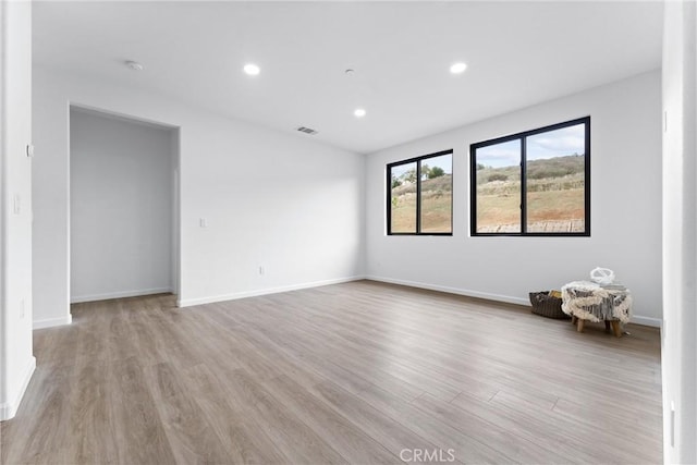 spare room with recessed lighting, wood finished floors, visible vents, and baseboards