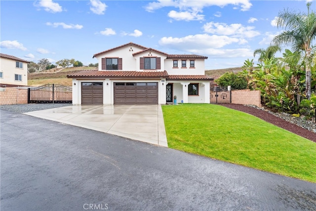 mediterranean / spanish home with a front lawn, a tiled roof, concrete driveway, stucco siding, and a gate