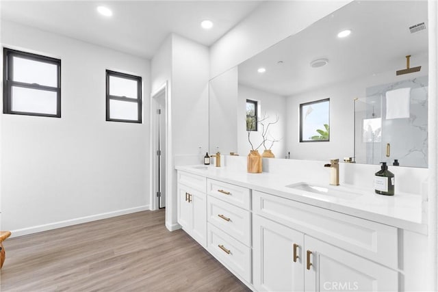 full bathroom with wood finished floors, visible vents, a marble finish shower, double vanity, and a sink