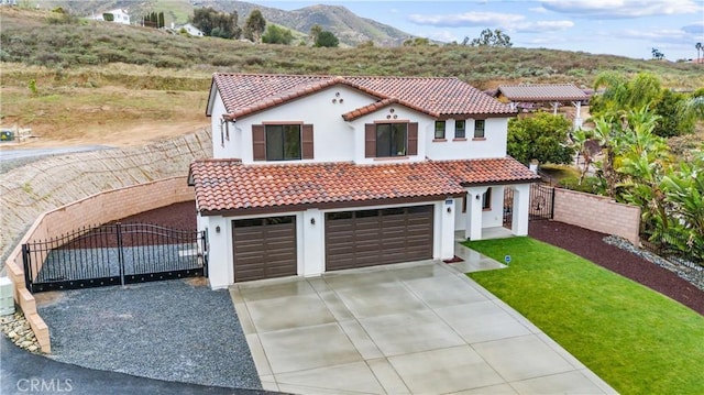 mediterranean / spanish-style house with fence, a tile roof, driveway, a mountain view, and a gate