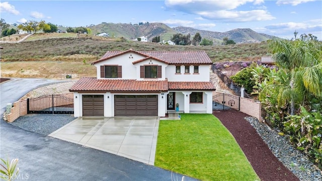 mediterranean / spanish house with a front yard, a gate, fence, a tiled roof, and a mountain view