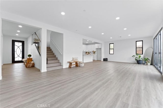 living area featuring stairway, recessed lighting, baseboards, and light wood-style floors