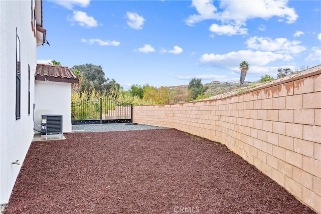 view of yard featuring central AC unit, fence private yard, and a gate