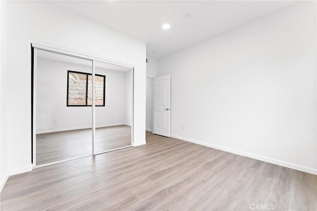 unfurnished bedroom with recessed lighting, baseboards, a closet, and light wood finished floors