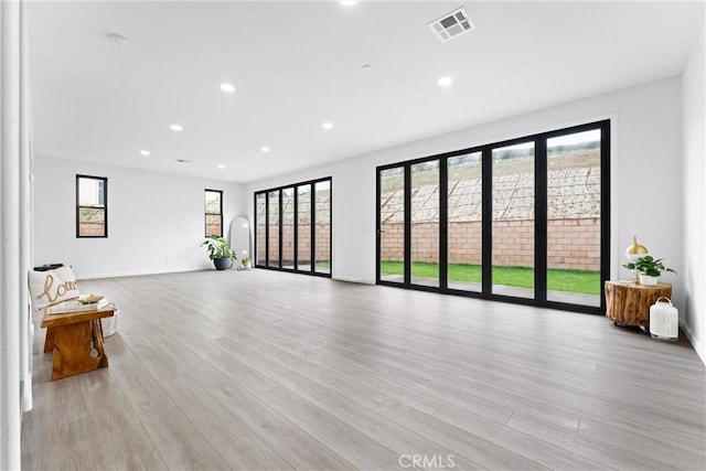 living room with recessed lighting, visible vents, light wood-style flooring, and a wealth of natural light