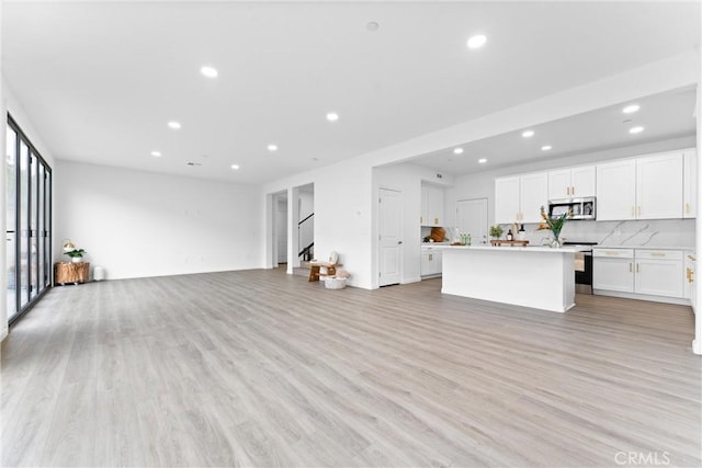 unfurnished living room featuring stairs, recessed lighting, and light wood-type flooring