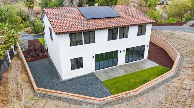 exterior space with solar panels, a tile roof, a fenced backyard, and stucco siding