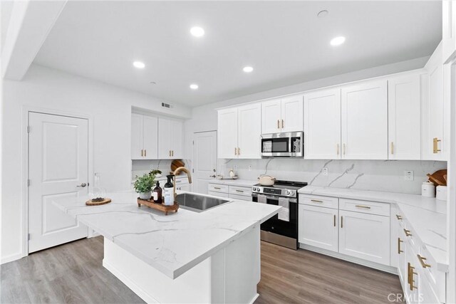 kitchen with a sink, appliances with stainless steel finishes, white cabinets, and light wood finished floors