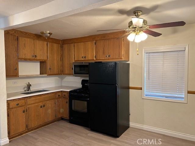 kitchen featuring brown cabinets, black appliances, light wood-style floors, and a sink