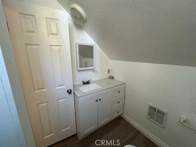 bathroom with visible vents, vanity, lofted ceiling, wood finished floors, and a textured ceiling