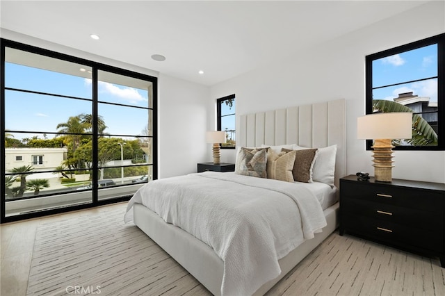 bedroom featuring a wall of windows, light wood-style flooring, recessed lighting, and access to outside