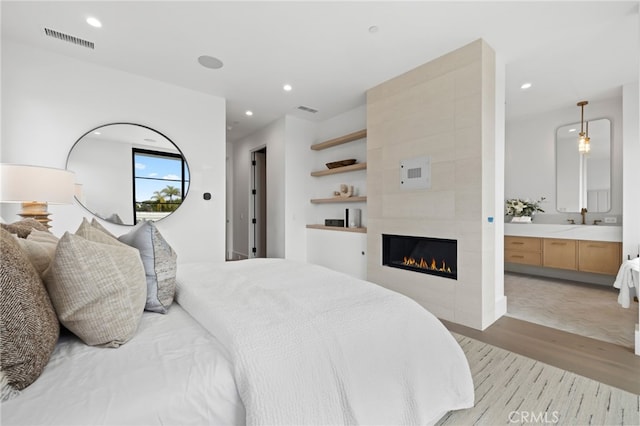 bedroom with a tiled fireplace, visible vents, recessed lighting, and light wood-type flooring