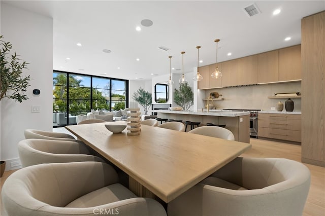 kitchen featuring visible vents, modern cabinets, a center island with sink, open floor plan, and stainless steel stove