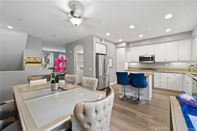 dining space featuring light wood-type flooring, visible vents, recessed lighting, arched walkways, and washer / dryer