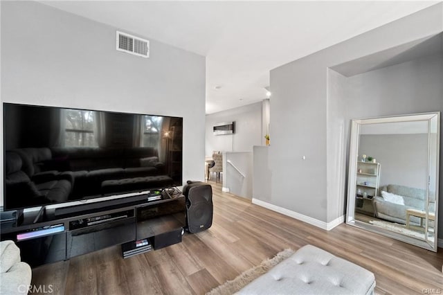 living room with wood finished floors, visible vents, and baseboards