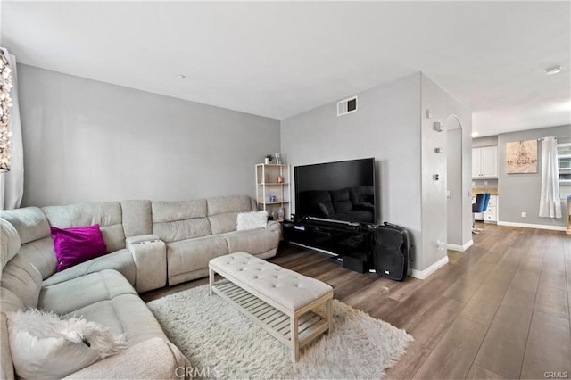 living area featuring wood finished floors, visible vents, and baseboards