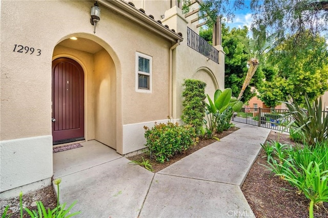 entrance to property with stucco siding and fence