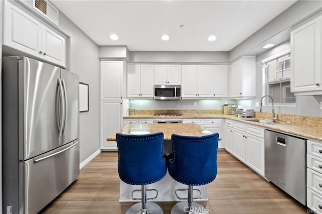 kitchen with visible vents, a sink, white cabinetry, appliances with stainless steel finishes, and light wood finished floors