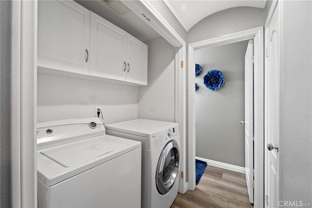 clothes washing area with baseboards, cabinet space, separate washer and dryer, and light wood-style flooring