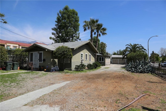 view of front of property featuring dirt driveway and fence