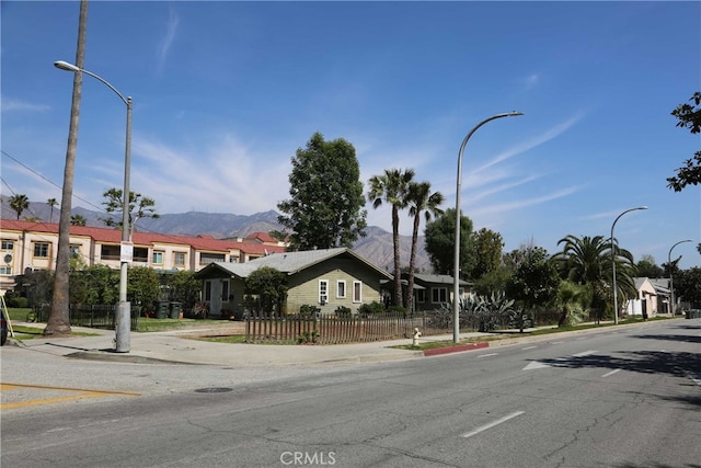 view of street featuring sidewalks, street lighting, a mountain view, and curbs