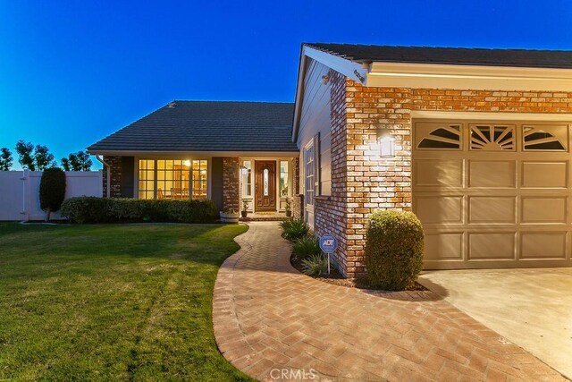 view of front of house with a front yard, an attached garage, and brick siding