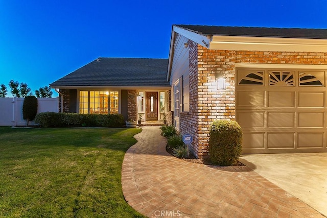 view of front of property featuring a front yard, brick siding, and an attached garage