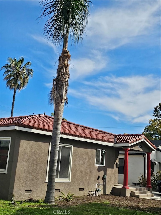 view of property exterior with crawl space, a tile roof, and stucco siding