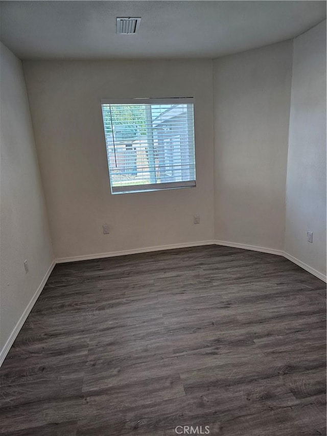 unfurnished room featuring visible vents, baseboards, and dark wood-style flooring