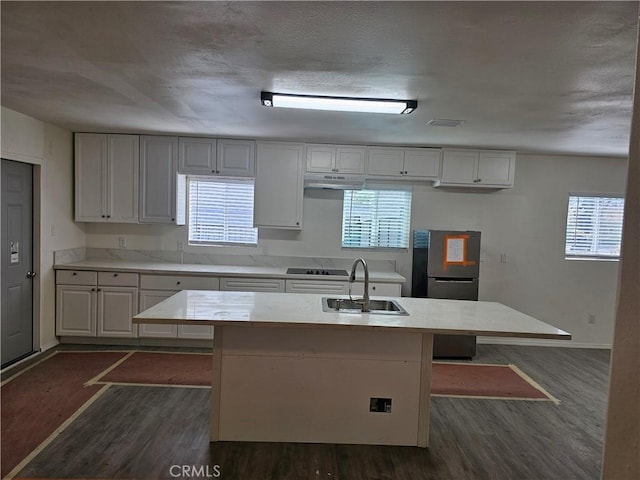 kitchen with a sink, dark wood-style flooring, light countertops, and freestanding refrigerator