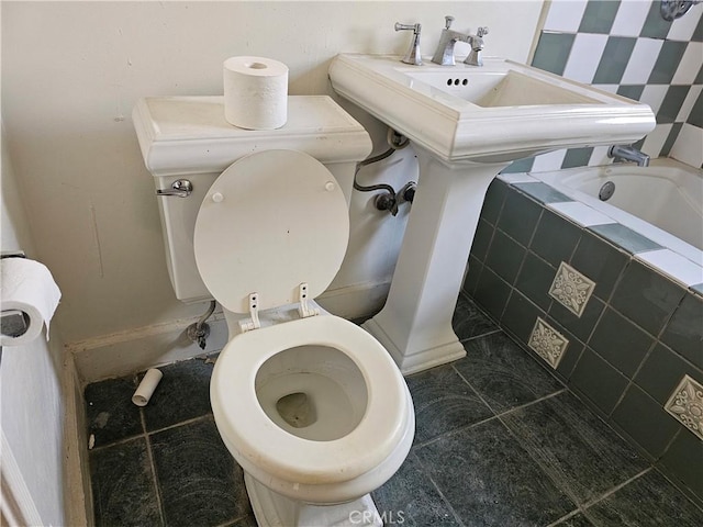 bathroom featuring a relaxing tiled tub, toilet, and tile patterned flooring