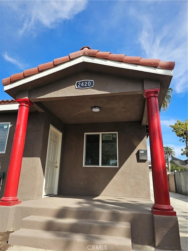 view of front of property featuring covered porch, a tile roof, and stucco siding