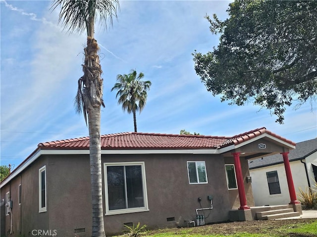 view of front of home with stucco siding, a tile roof, and crawl space