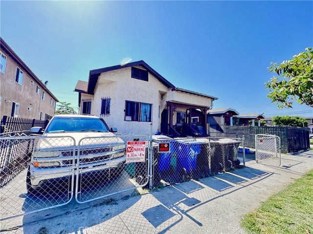 view of front facade with a gate, stucco siding, and fence