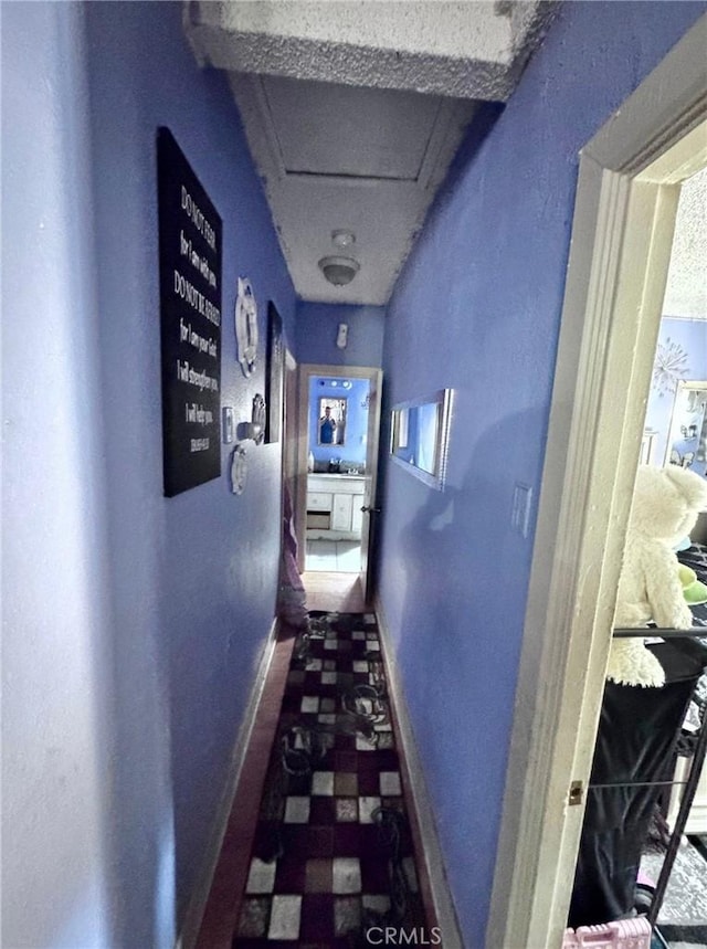 corridor with attic access and baseboards