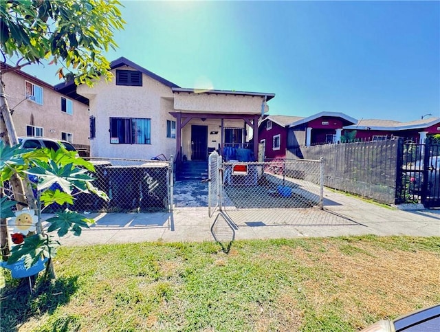 back of property with a gate, covered porch, a fenced front yard, and stucco siding