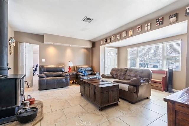 living area featuring a wood stove, light tile patterned floors, and visible vents